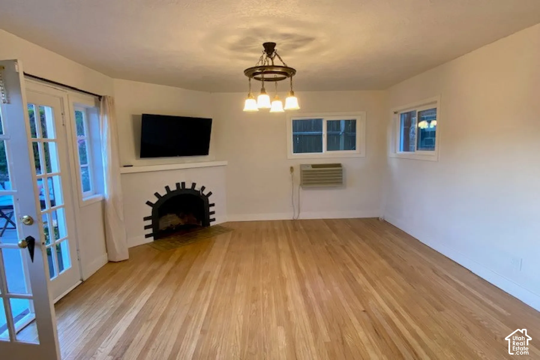 Interior space featuring wood-finish flooring, a decorative corner fireplace, a multi-pane glass entry door, and a circular iron chandelier
