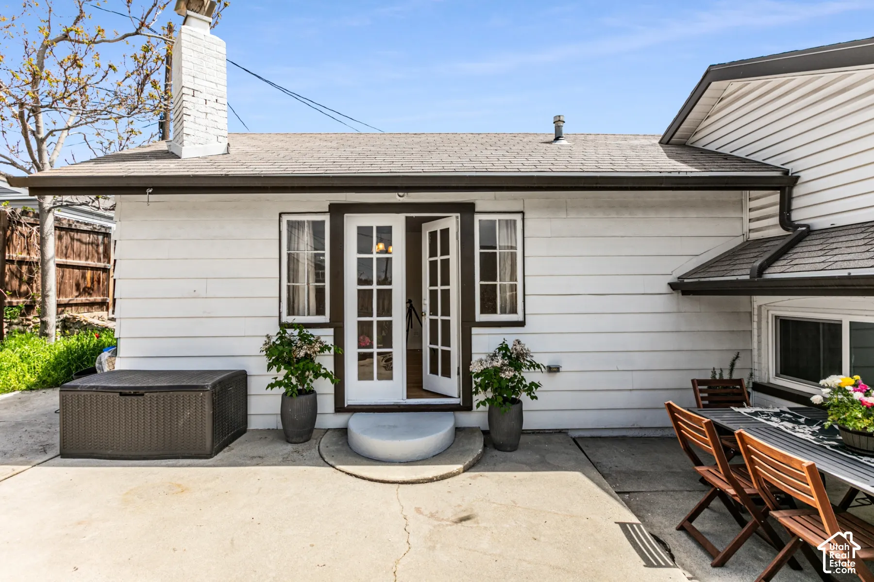 Exterior patio featuring white horizontal siding, a painted brick chimney, and French doors with glass panes