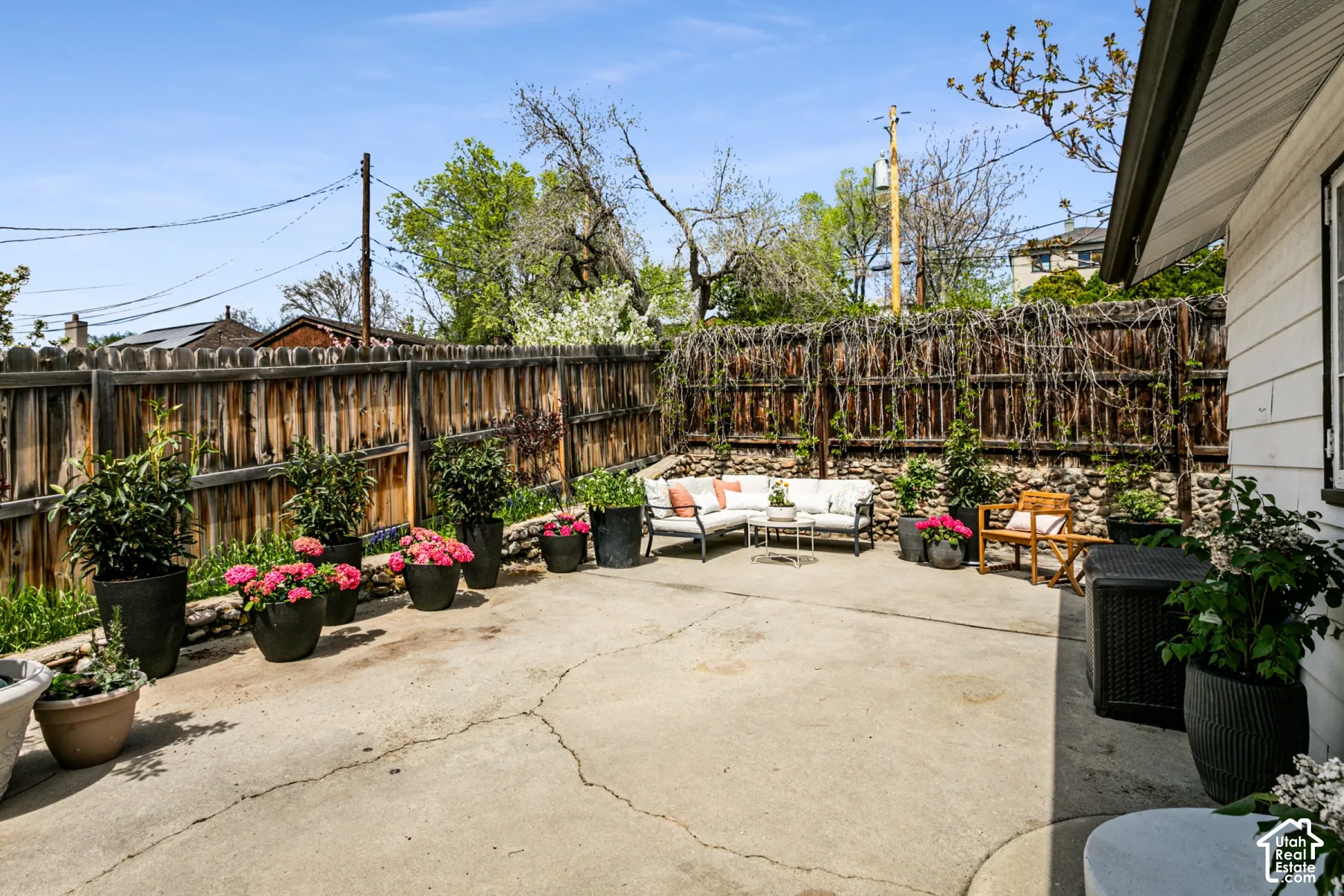 Concrete patio featuring a stacked stone retaining wall and full-height wood fencing