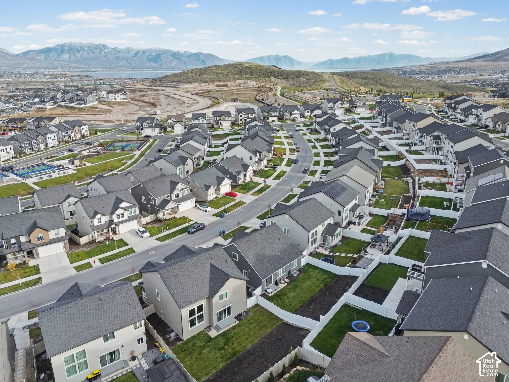 Aerial perspective featuring residential lots with fenced backyards, paved street infrastructure, and a prominent mountain range backdrop
