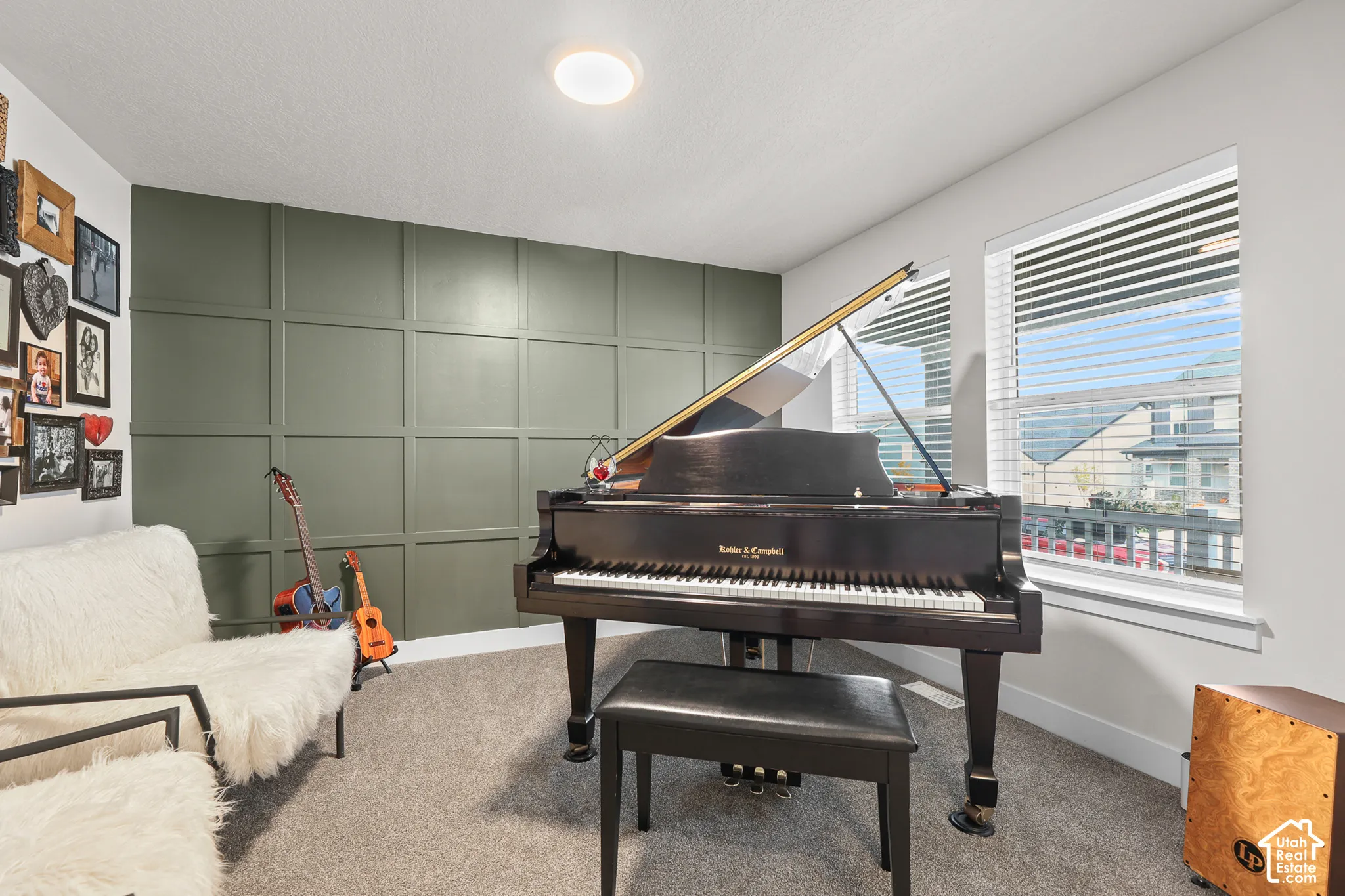Room featuring an olive green grid-patterned accent wall, wall-to-wall carpeting, and double-pane windows with horizontal blinds