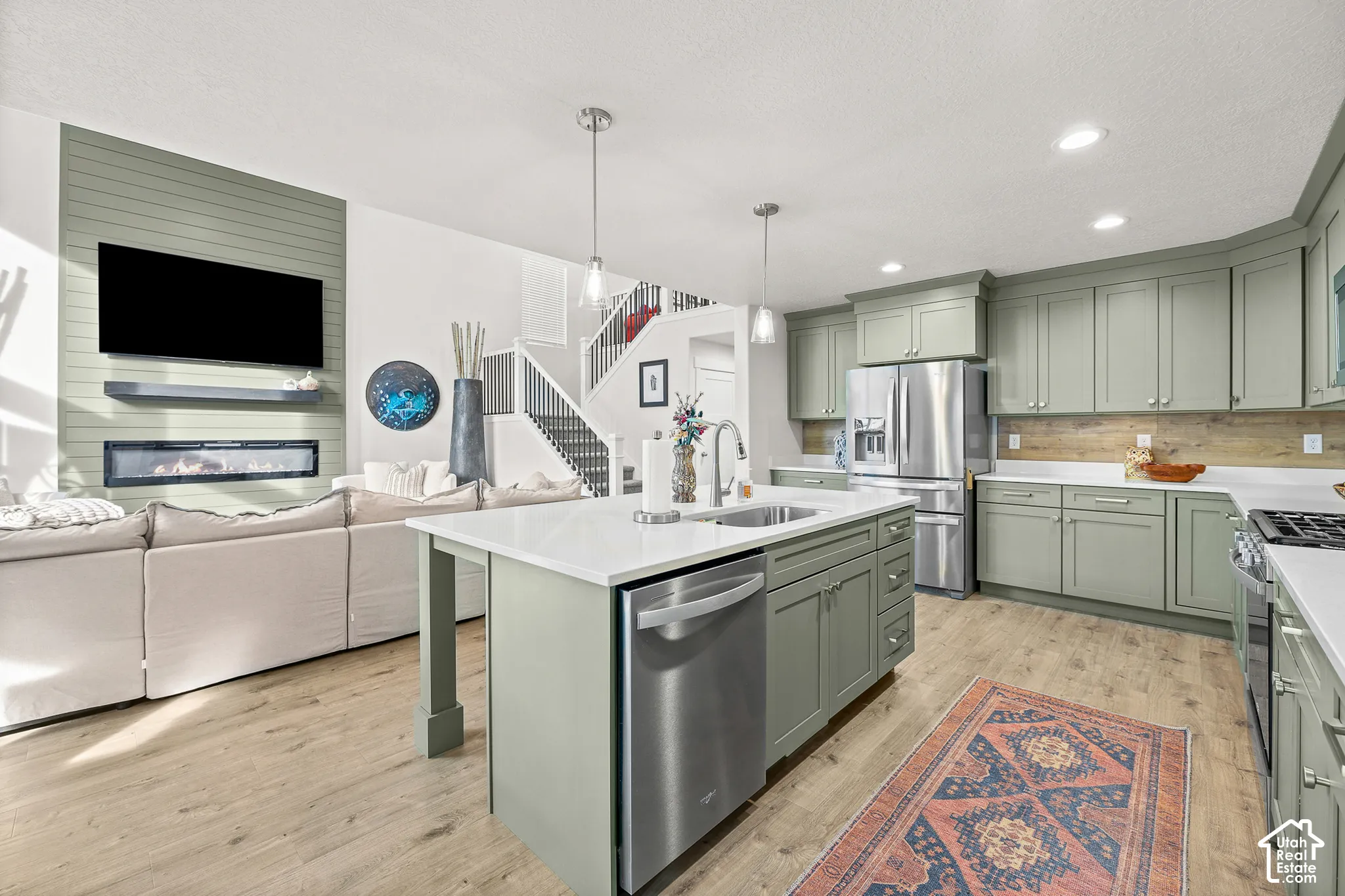 Kitchen featuring shaker-style cabinetry, an expansive center island with an integrated stainless steel dishwasher and sink, and wood-finish flooring
