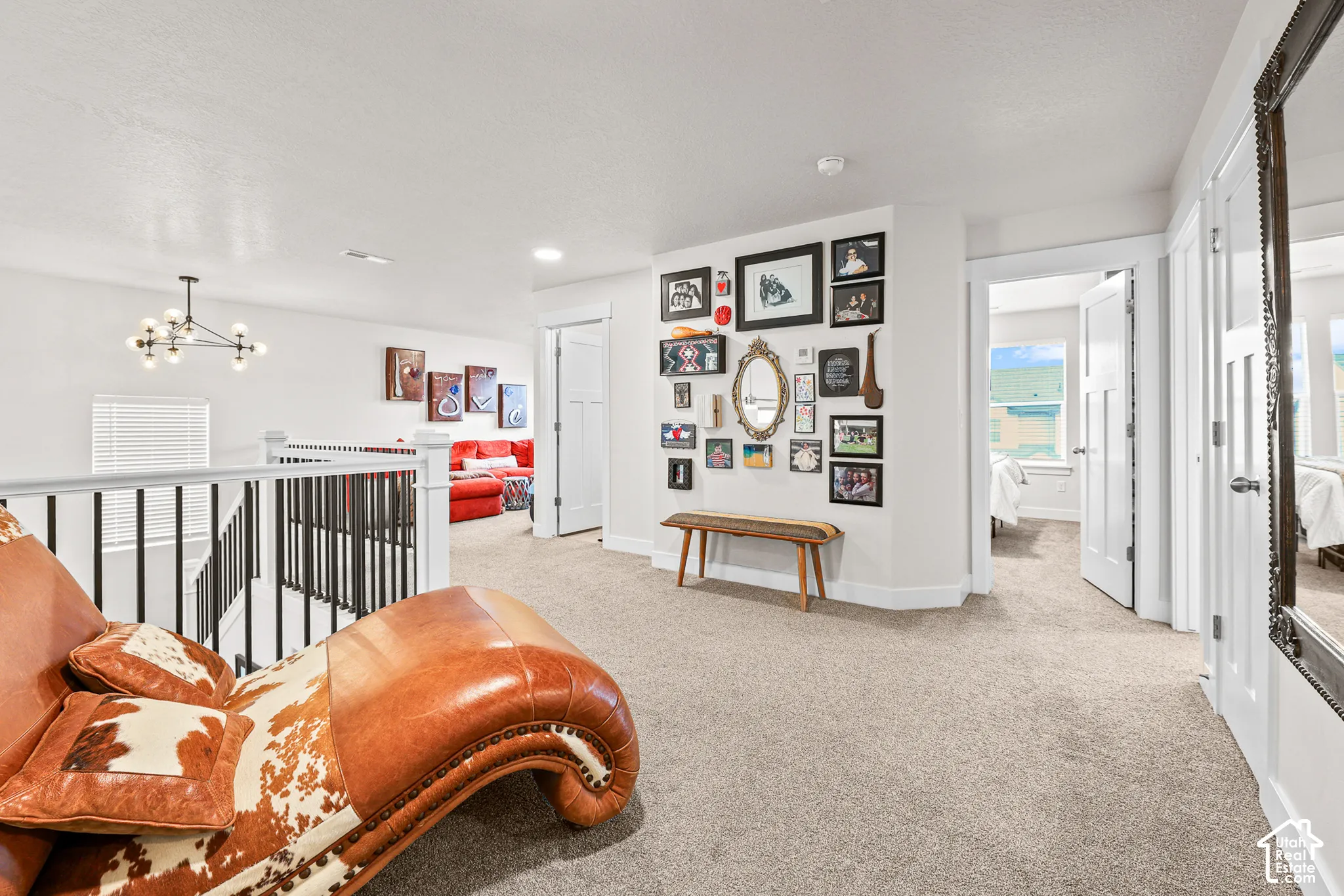 Neutral-toned interior featuring wall-to-wall carpeting, black metal spindle railing, multi-bulb modern chandelier, and multi-panel doors