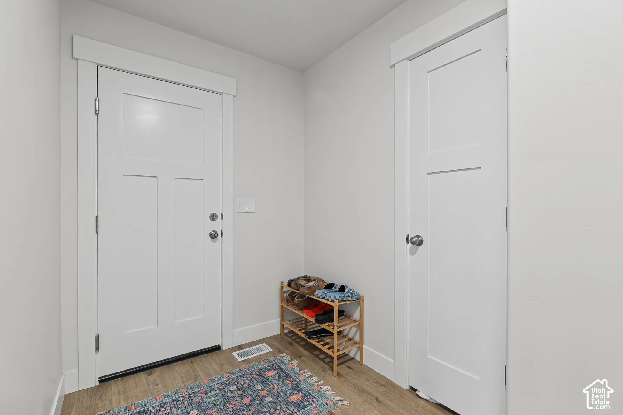 Entryway featuring white-paneled interior doors, craftsman-style casing, and wood-finish flooring