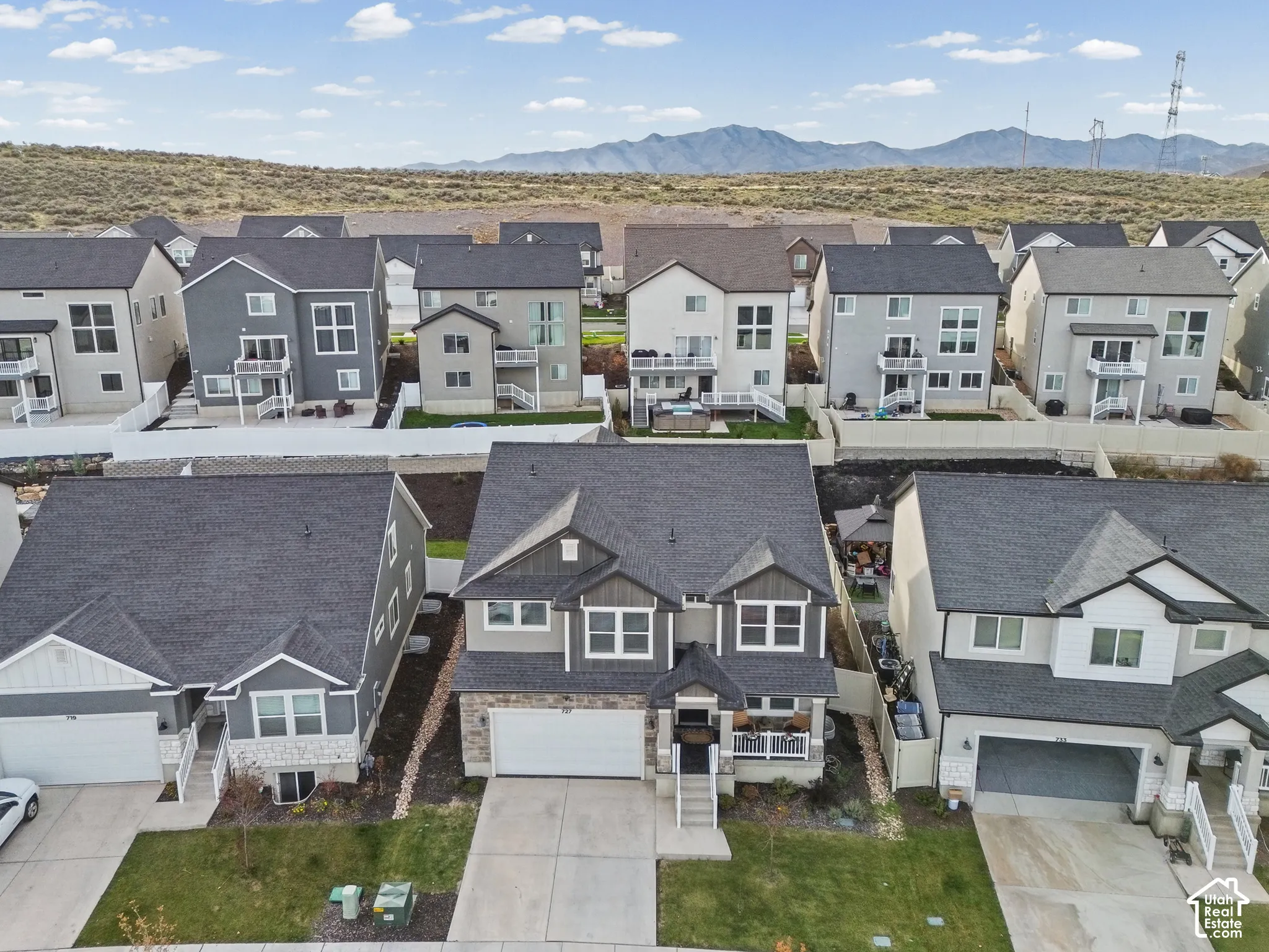 Two-story residence featuring a multi-material facade of stone veneer and horizontal siding, an attached two-car garage, an asphalt shingle roof, and a front-facing covered porch with column supports