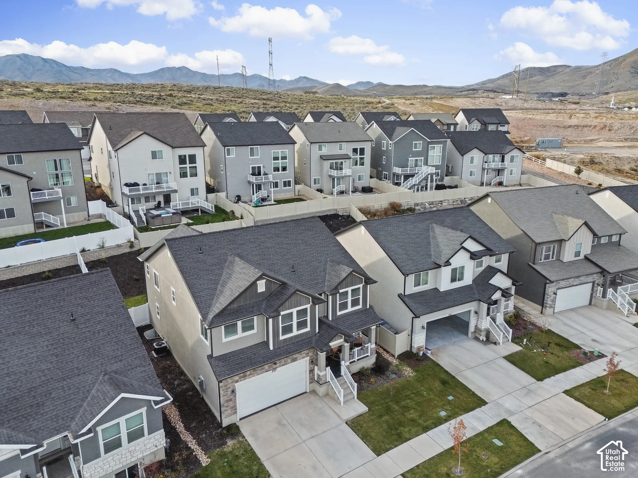 Multi-level residential exterior featuring a two-car garage, stone veneer siding accents, shingled roofing, and mountain backdrop