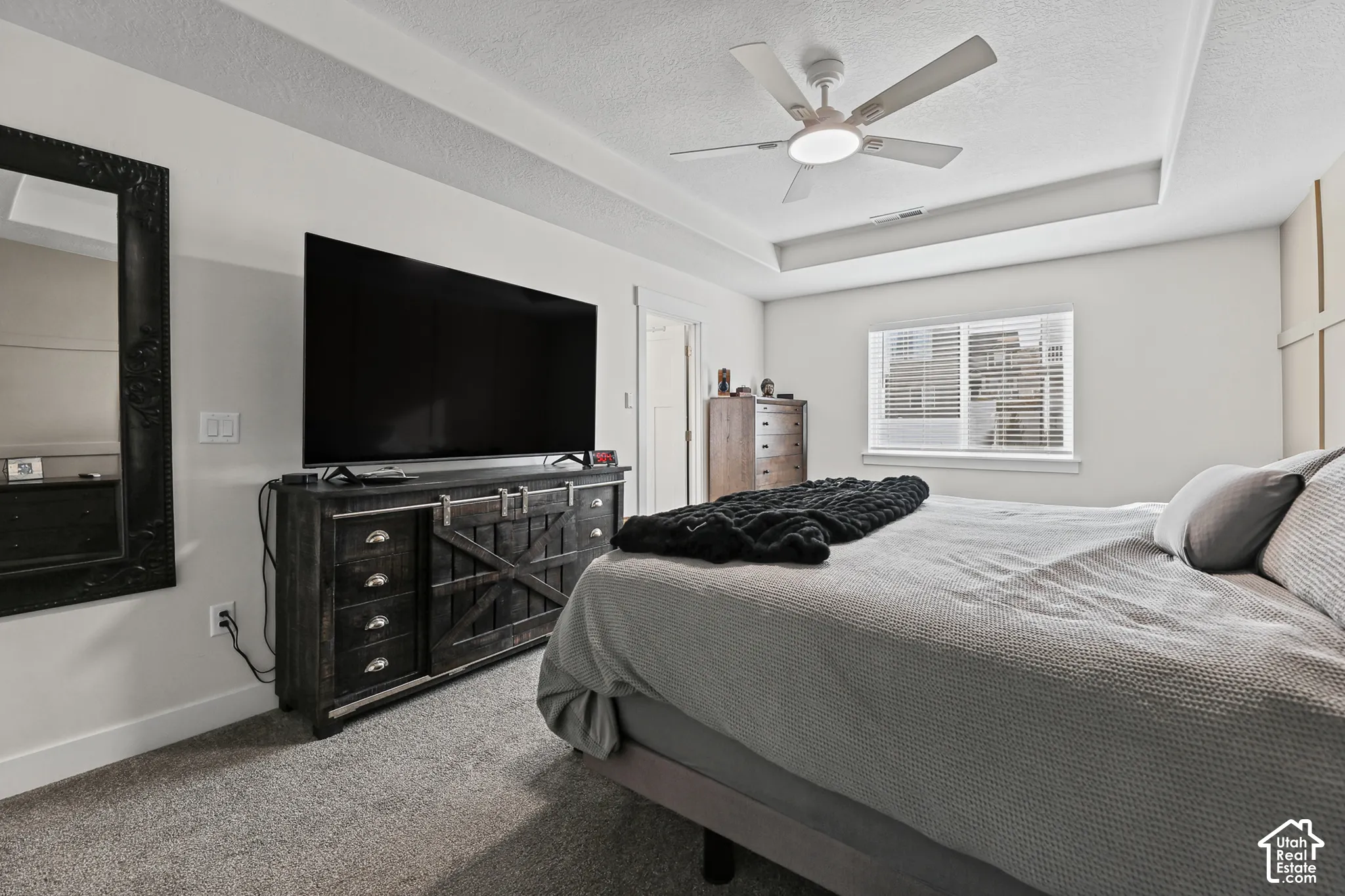 Tray ceiling featuring a central ceiling fan with integrated lighting, wall molding, and carpeted flooring