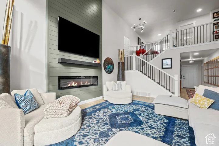 Two-story living area featuring a floor-to-ceiling shiplap accent wall, linear electric fireplace, floating mantel, and staircase with wrought iron balusters