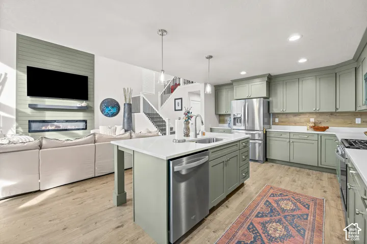 Kitchen featuring shaker-style cabinetry, an expansive center island with an integrated stainless steel dishwasher and sink, and wood-finish flooring