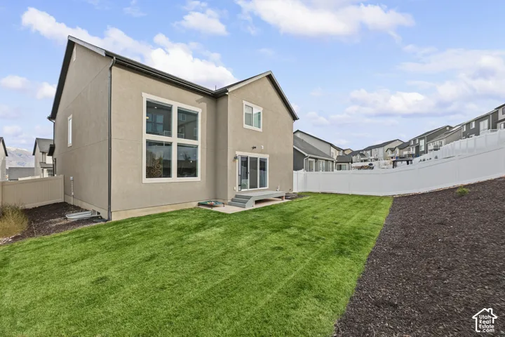 Exterior featuring stucco siding, multi-pane windows, sliding glass door with stairs, and a fenced backyard