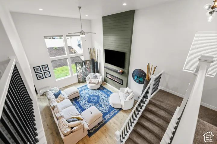 Two-story volume ceiling with floor-to-ceiling accent wall, vertical plank detailing, linear electric fireplace, recessed lighting, and wood-finish flooring