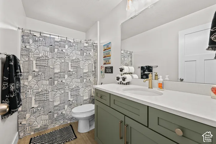 Bathroom featuring a green-toned shaker-style vanity, solid-surface countertop with an integrated oval sink, brass-finish faucet, and oversized wall-mounted mirror
