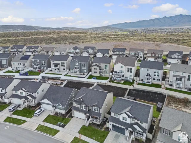 Aerial perspective featuring multi-story residential architecture, attached garages, paved driveways, fenced rear yards, and mountain backdrop