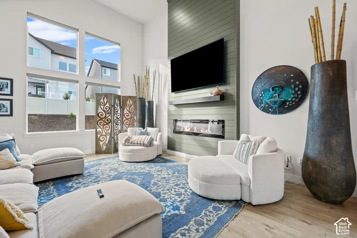 Double-height ceilings, floor-to-ceiling windows, linear electric fireplace, full-height paneled chimney breast, and wood-finish flooring
