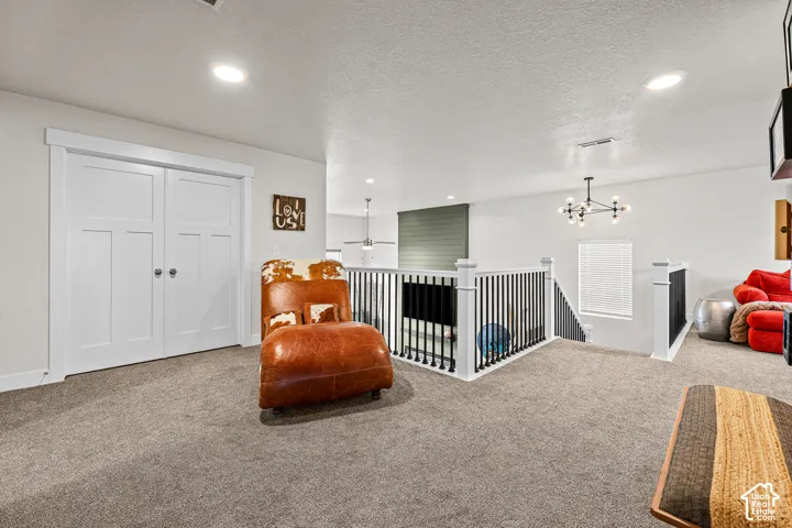 Carpeted open-concept space featuring double-panel interior doors, recessed lighting, a modern multi-arm chandelier, and a decorative railing with vertical balusters
