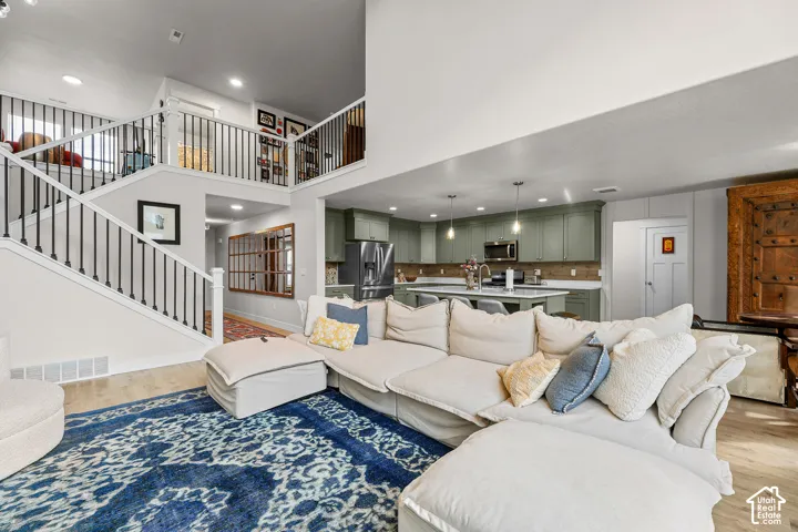 Open-concept interior featuring a double-height ceiling, custom cabinetry, kitchen island with stone-surface countertop, and a staircase with iron balusters