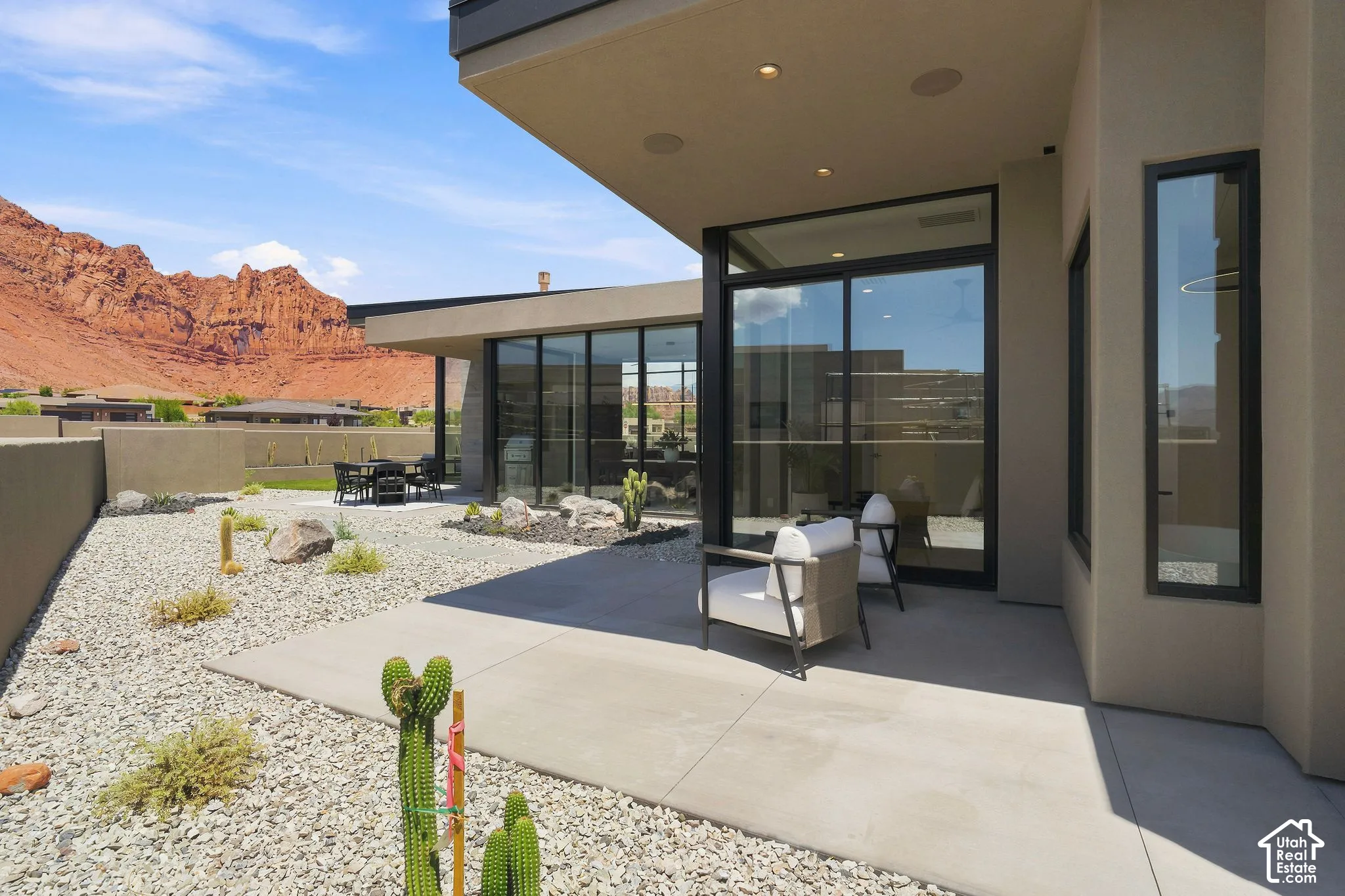Concrete patio with extensive sliding glass door systems, recessed ceiling lighting, xeriscaped ground cover, and mountain backdrop