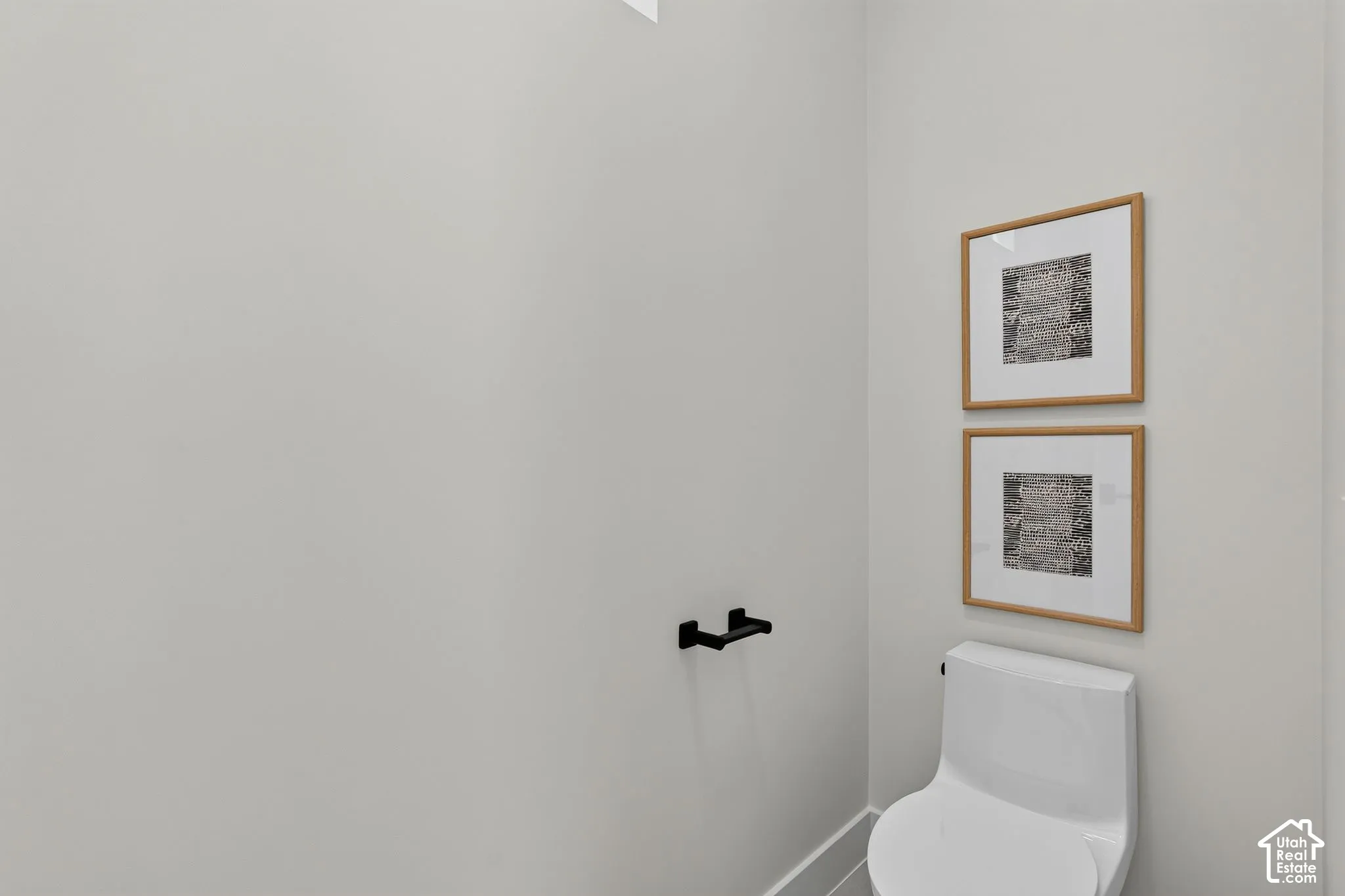 White two-piece elongated toilet featuring a matte black wall-mounted toilet paper holder