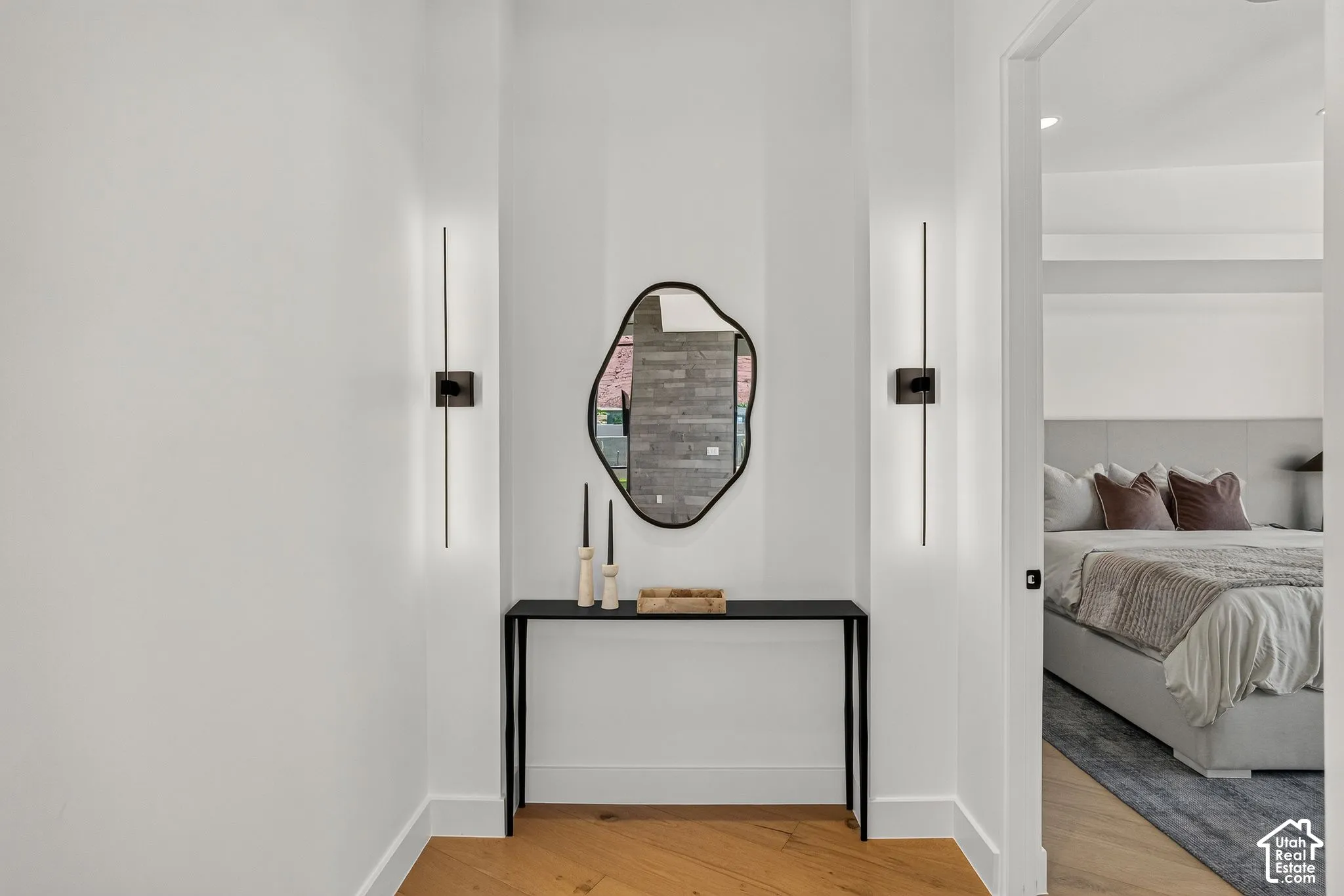 Alcove featuring vertical linear wall-mounted light fixtures and wood-finish flooring