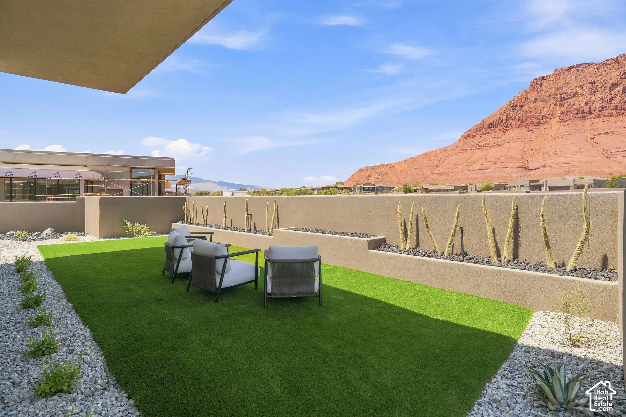 Private terrace featuring synthetic turf, tiered concrete retaining walls, integrated desert landscaping, and prominent red rock mountain backdrop