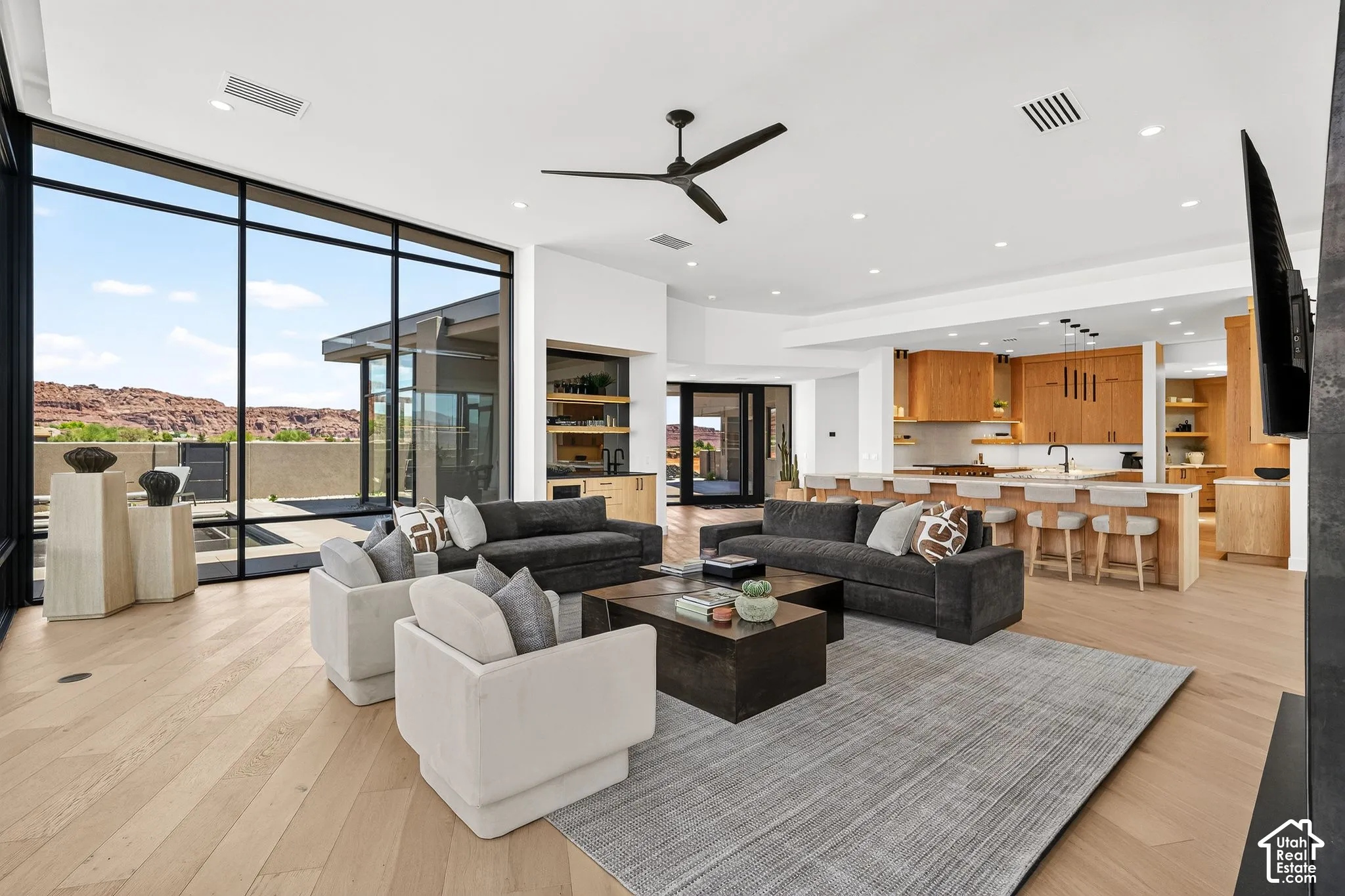 Floor-to-ceiling glass walls, wood-finish flooring, custom wood cabinetry, stone countertops, and recessed lighting
