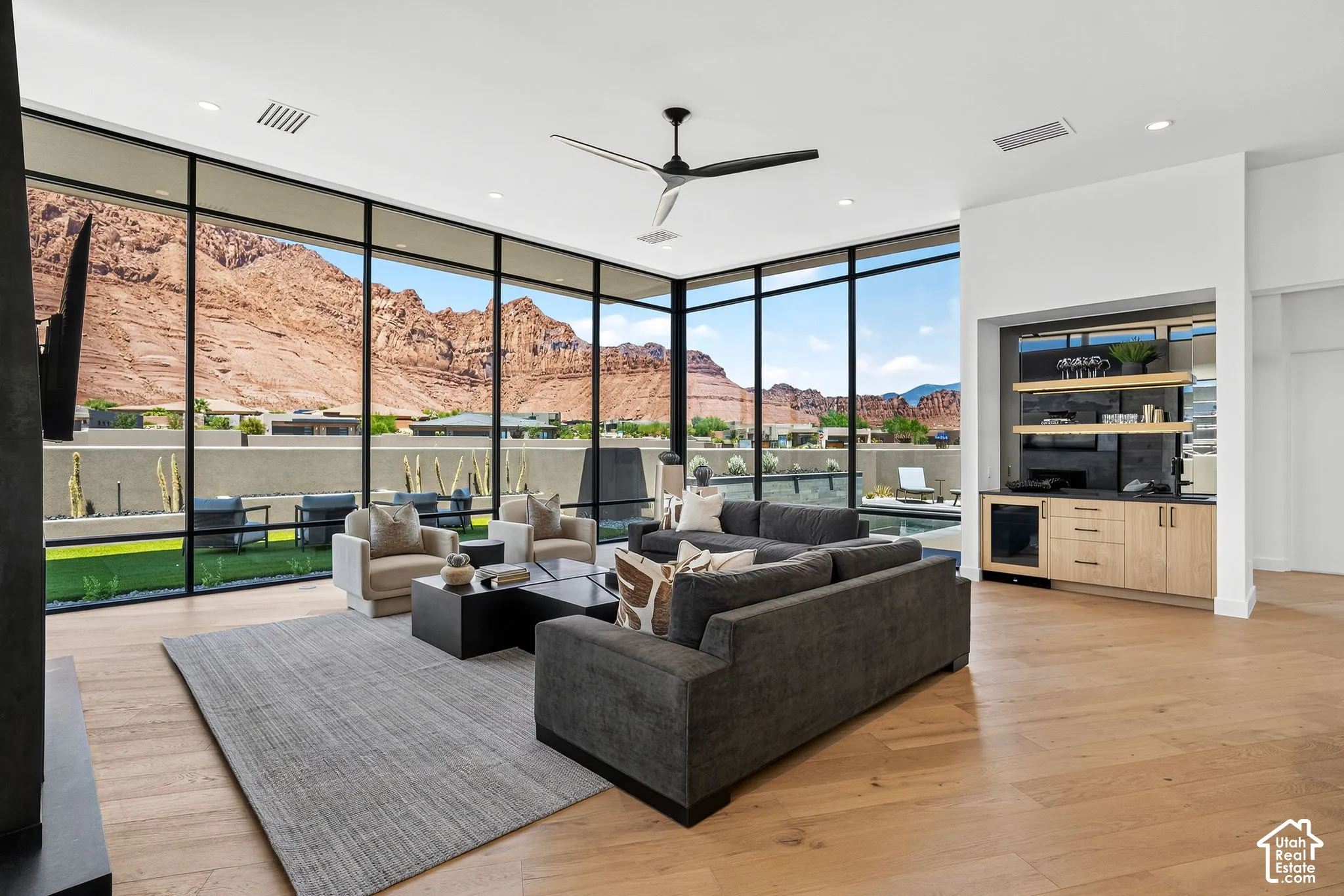 Floor-to-ceiling windows with mountain scenery, light wood-finish flooring, built-in wet bar with cabinetry, integrated wine cooler, and recessed lighting