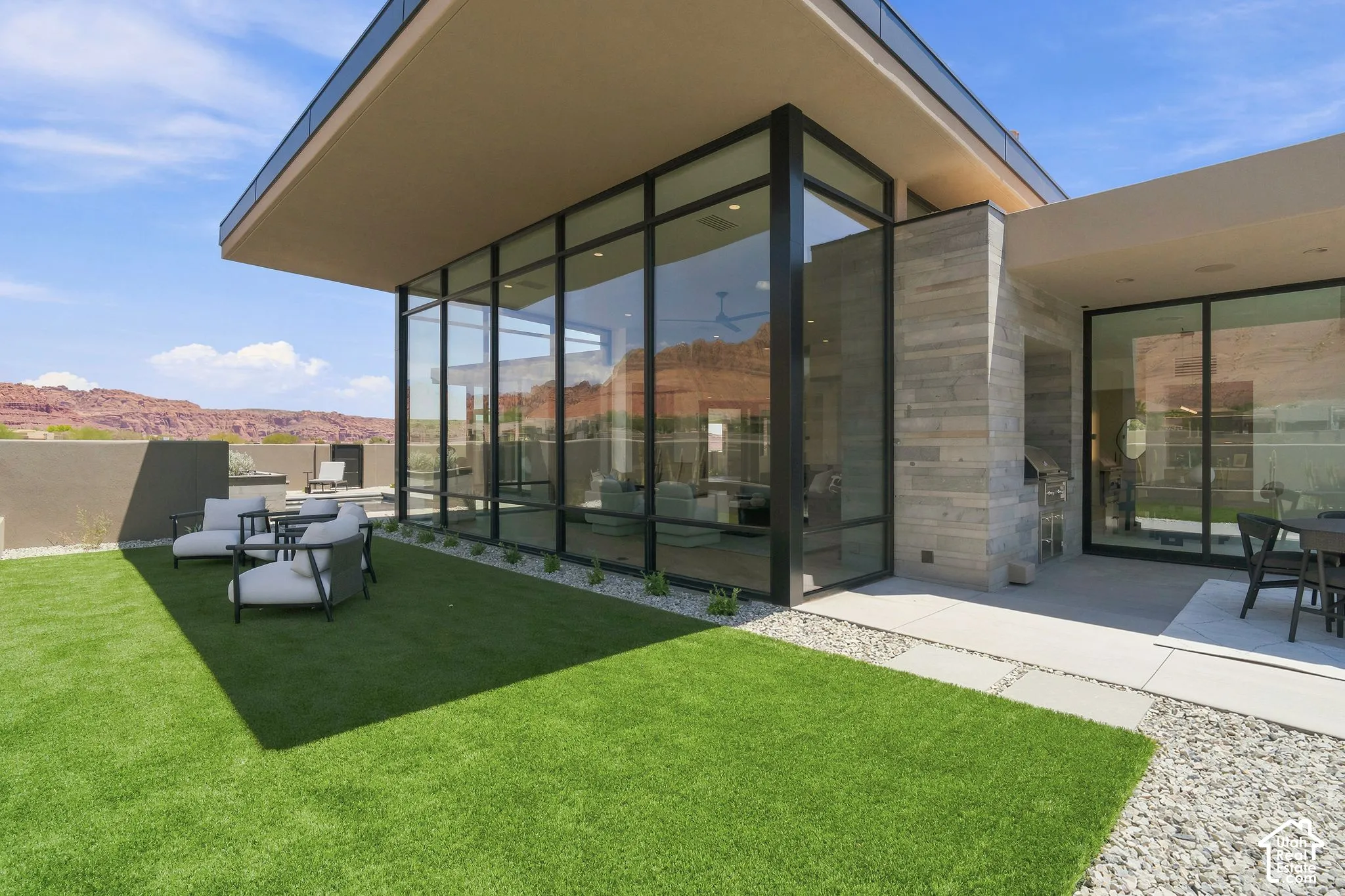 Modern architectural exterior featuring expansive floor-to-ceiling glass walls, natural stone facade detailing, and a cantilevered roofline