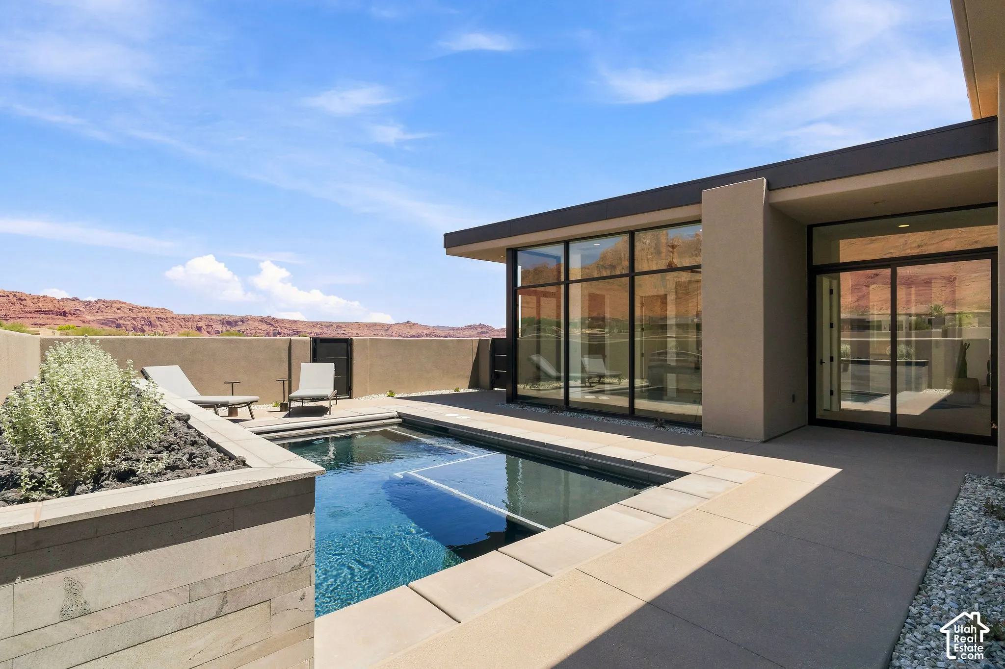 Outdoor pool featuring concrete decking, a stacked stone planter box, floor-to-ceiling windows, and mountain scenery