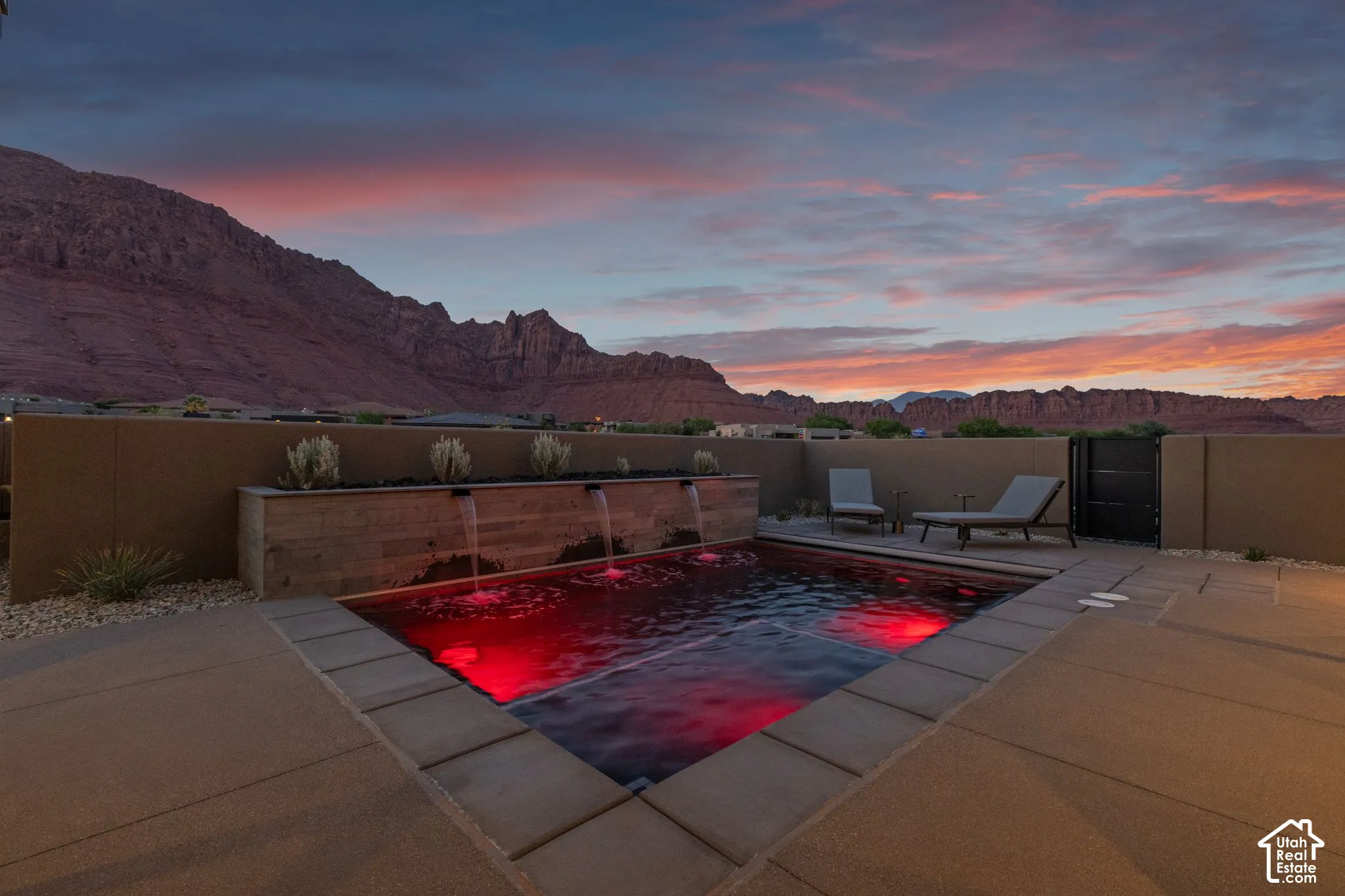 Plunge pool featuring a stone-clad water feature with three spillway fountains, a concrete patio surround, and a walled perimeter, set against a mountainous landscape