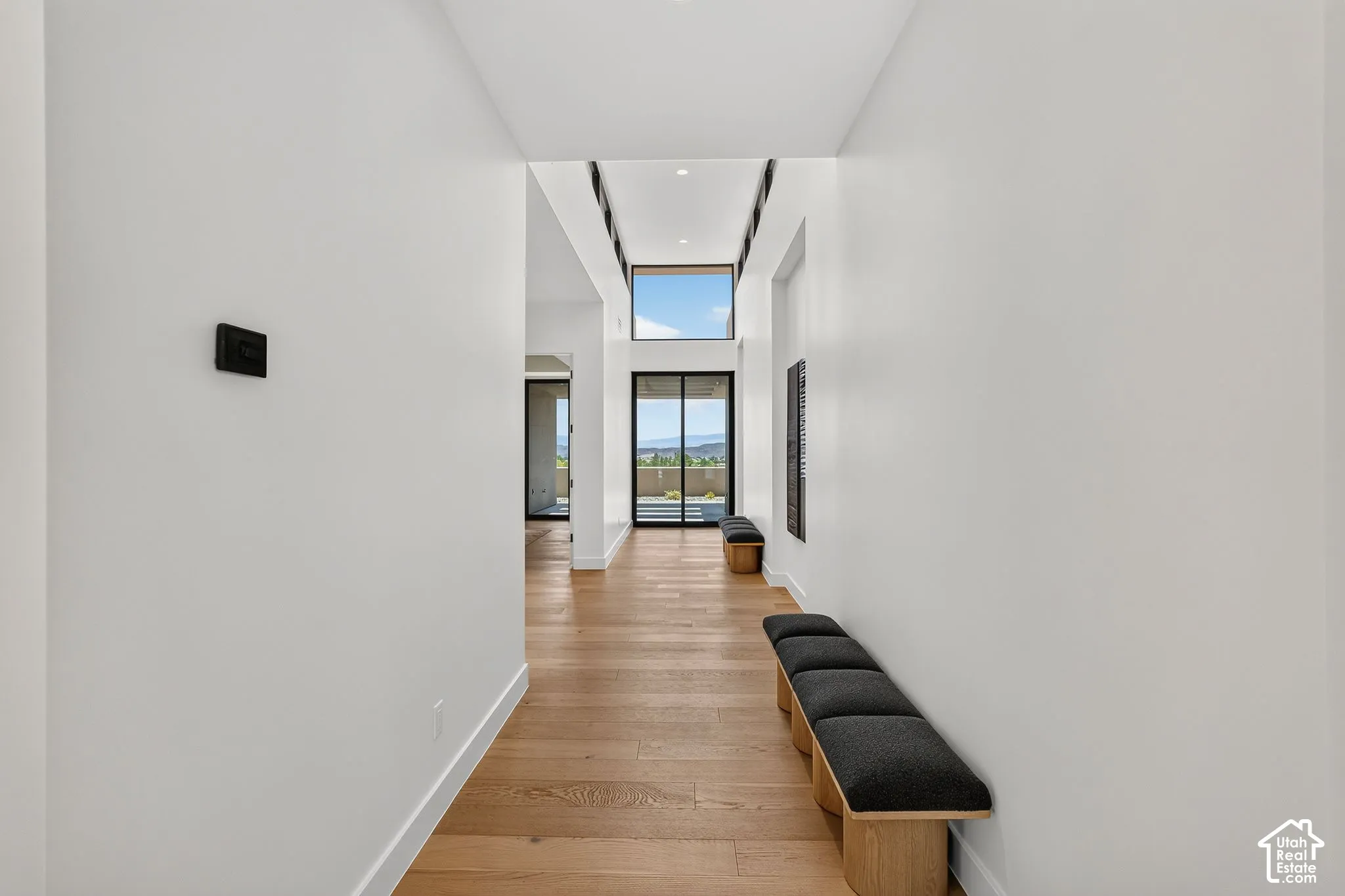 Hallway featuring wood-finish flooring, recessed lighting, and a dual-level window design with black-framed glass