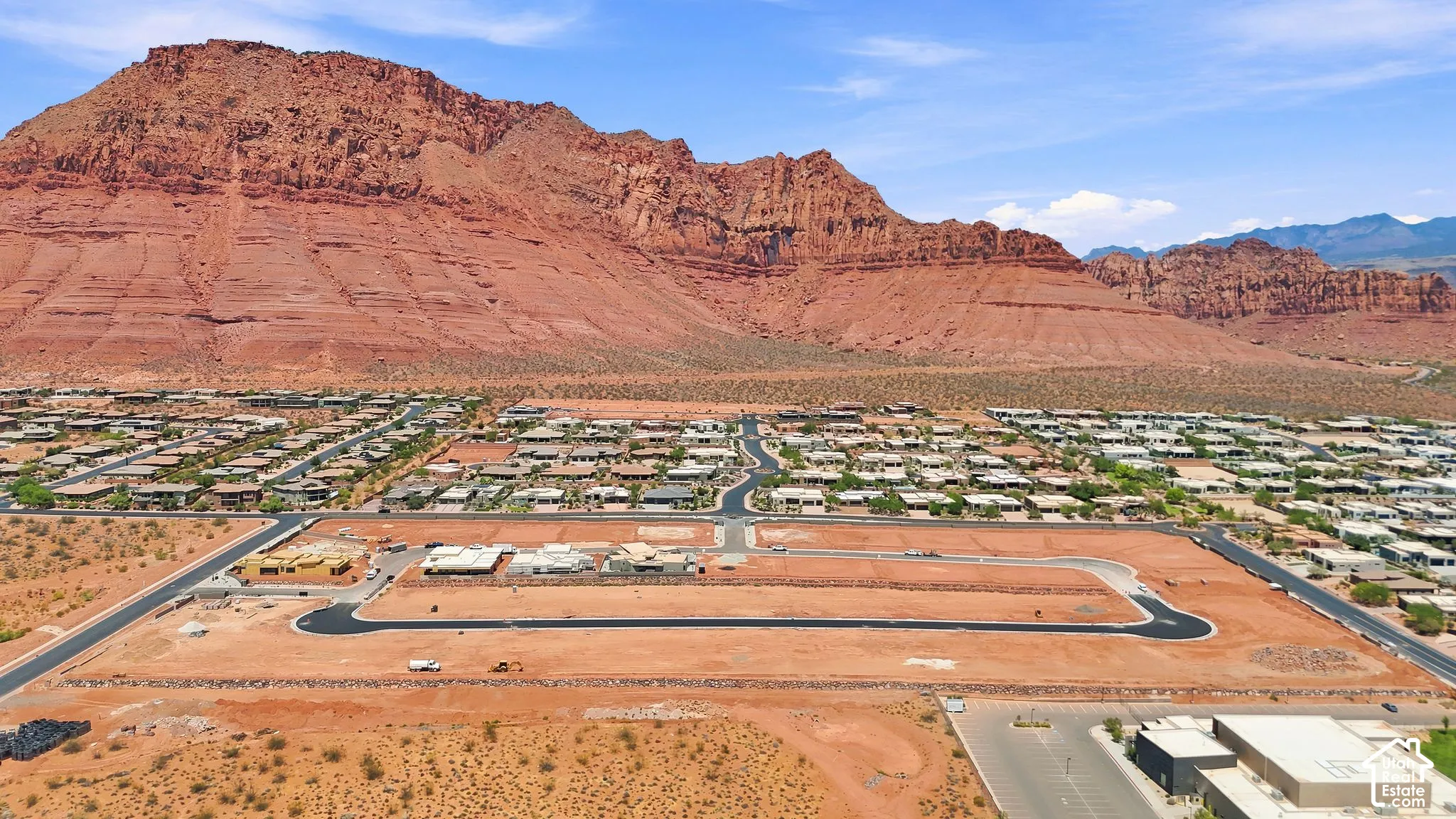 Aerial perspective of a vacant development lot featuring paved infrastructure and prominent red rock mountain backdrop