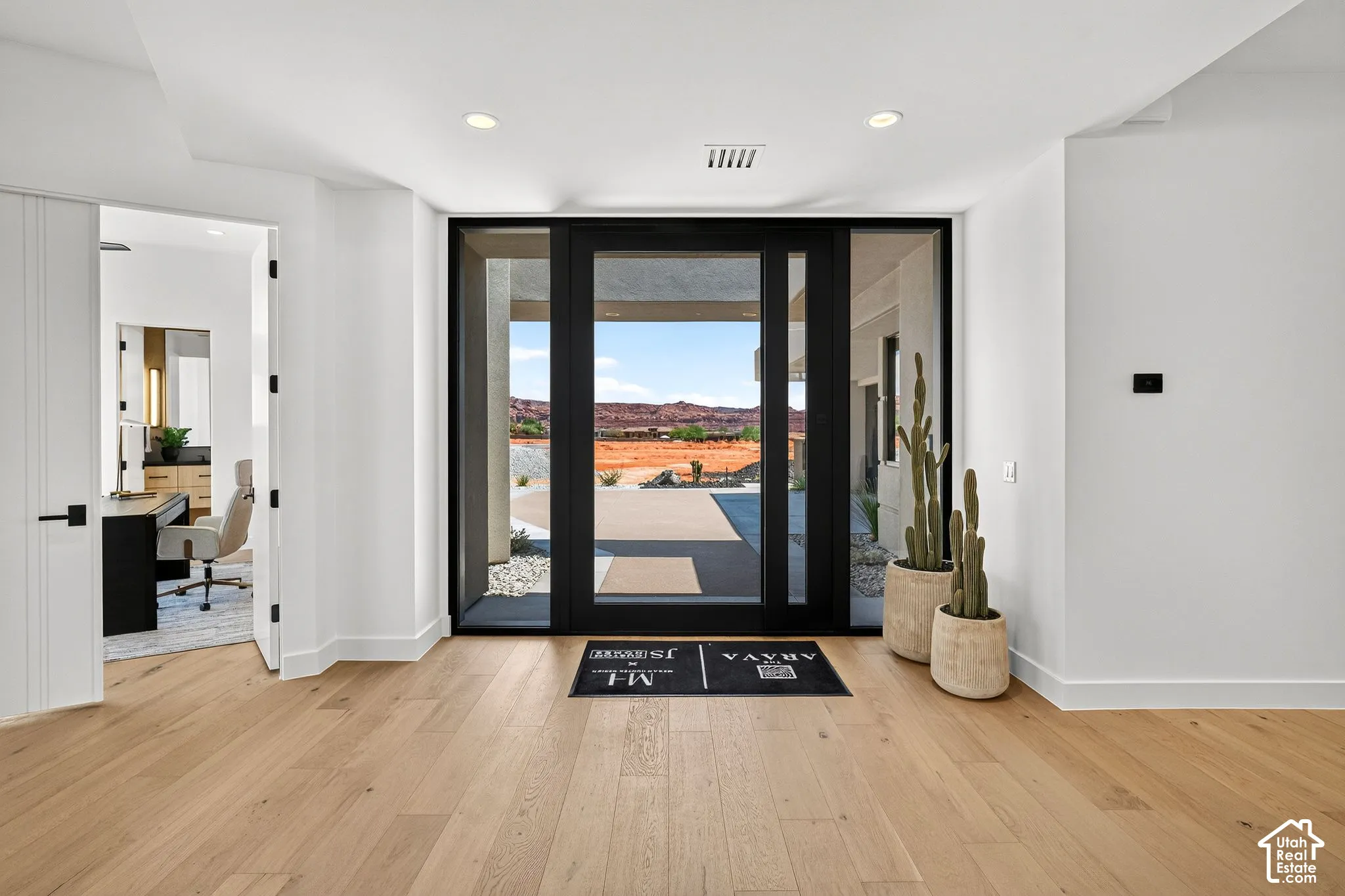Entryway featuring wide-plank wood-finish flooring, a black-framed glass pivot door, recessed lighting, and desert mountain backdrop