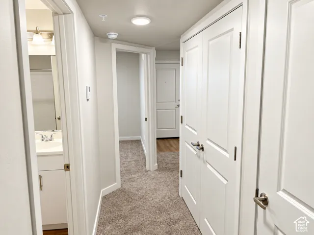 Hallway featuring neutral-toned carpeting, solid-core interior doors with satin nickel hardware, and recessed lighting