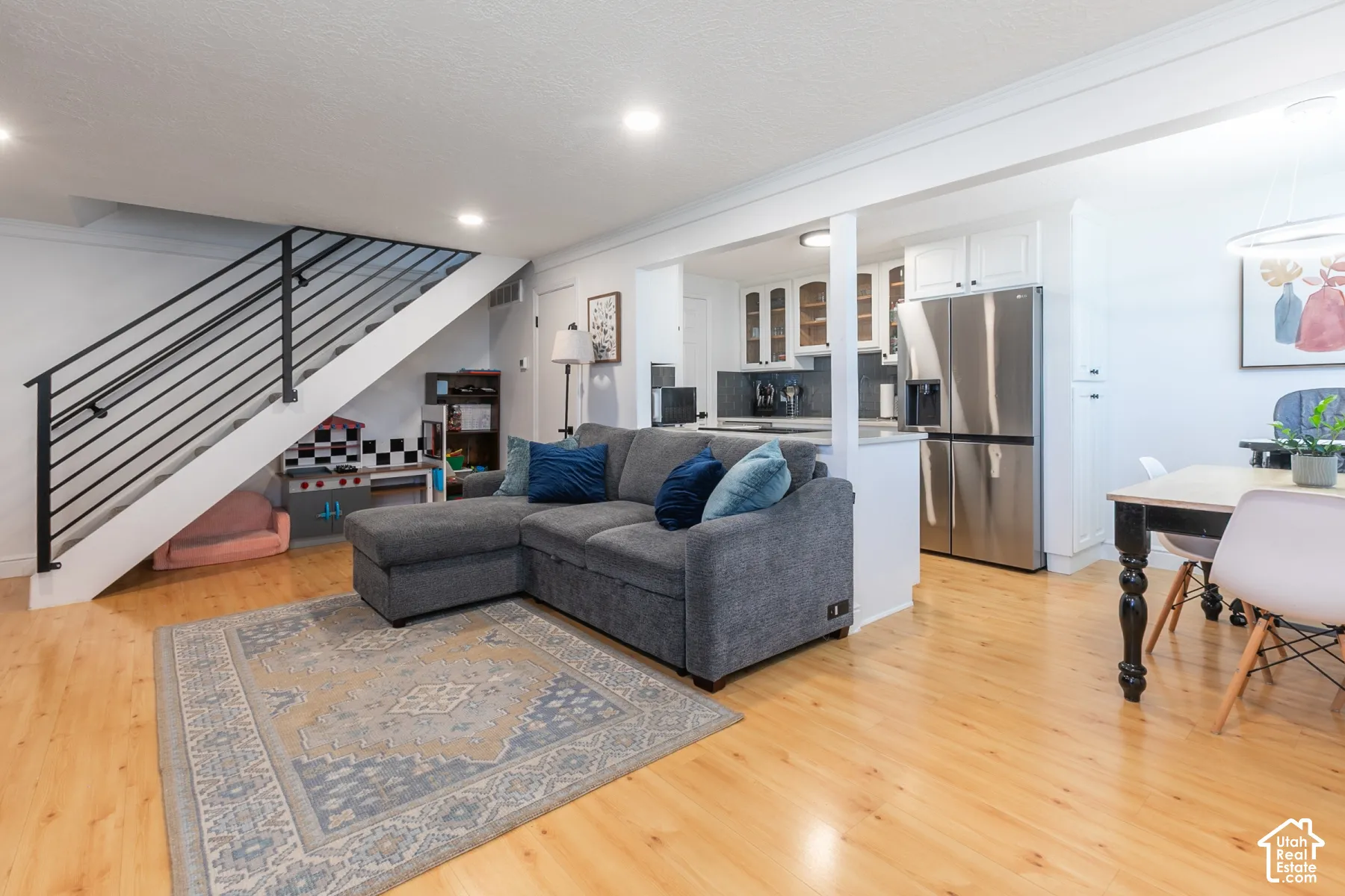 Open-concept area featuring wood-finish flooring, recessed lighting, and a staircase with black metal railings