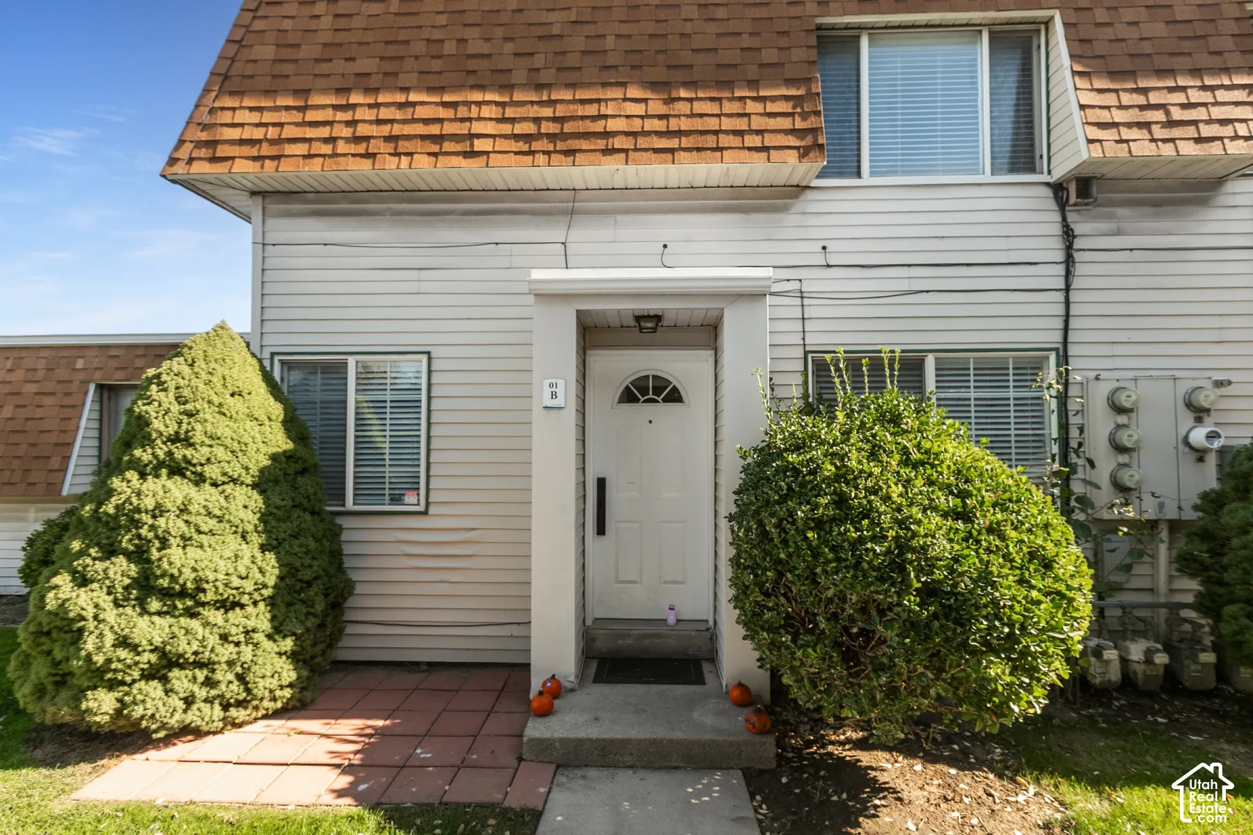 Exterior facade featuring horizontal siding, a mansard roofline, a central covered entryway, and a concrete porch