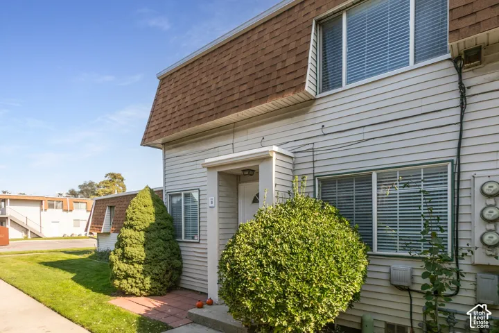 Exterior elevation featuring horizontal siding, a mansard-style roofline with asphalt shingles, a covered entryway, and multi-pane windows