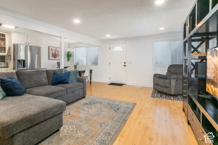 Open-concept interior featuring light wood-finish flooring, recessed lighting, and white cabinetry