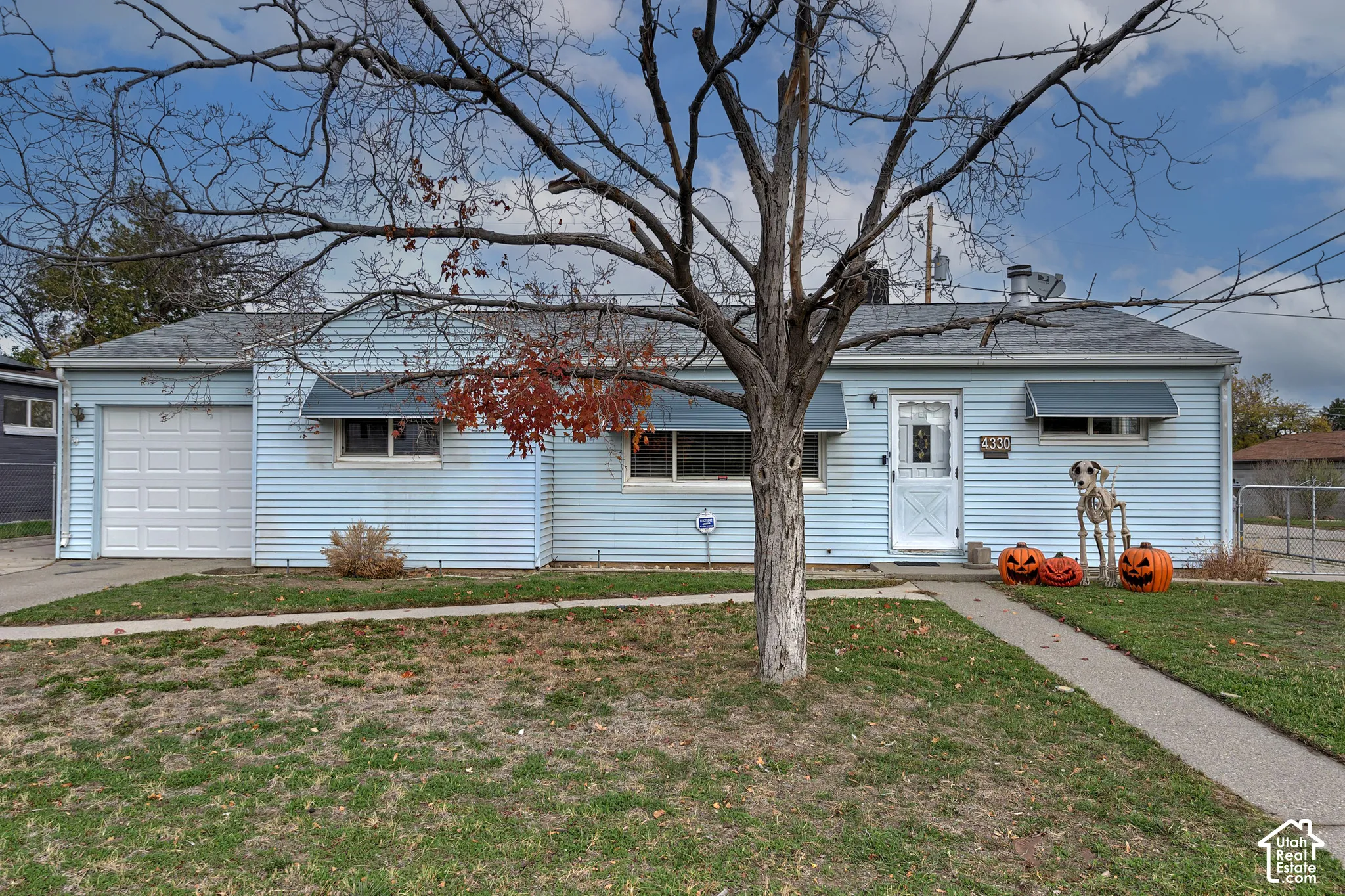 Single-story residence with horizontal siding, attached one-car garage, window awnings, and a concrete walkway