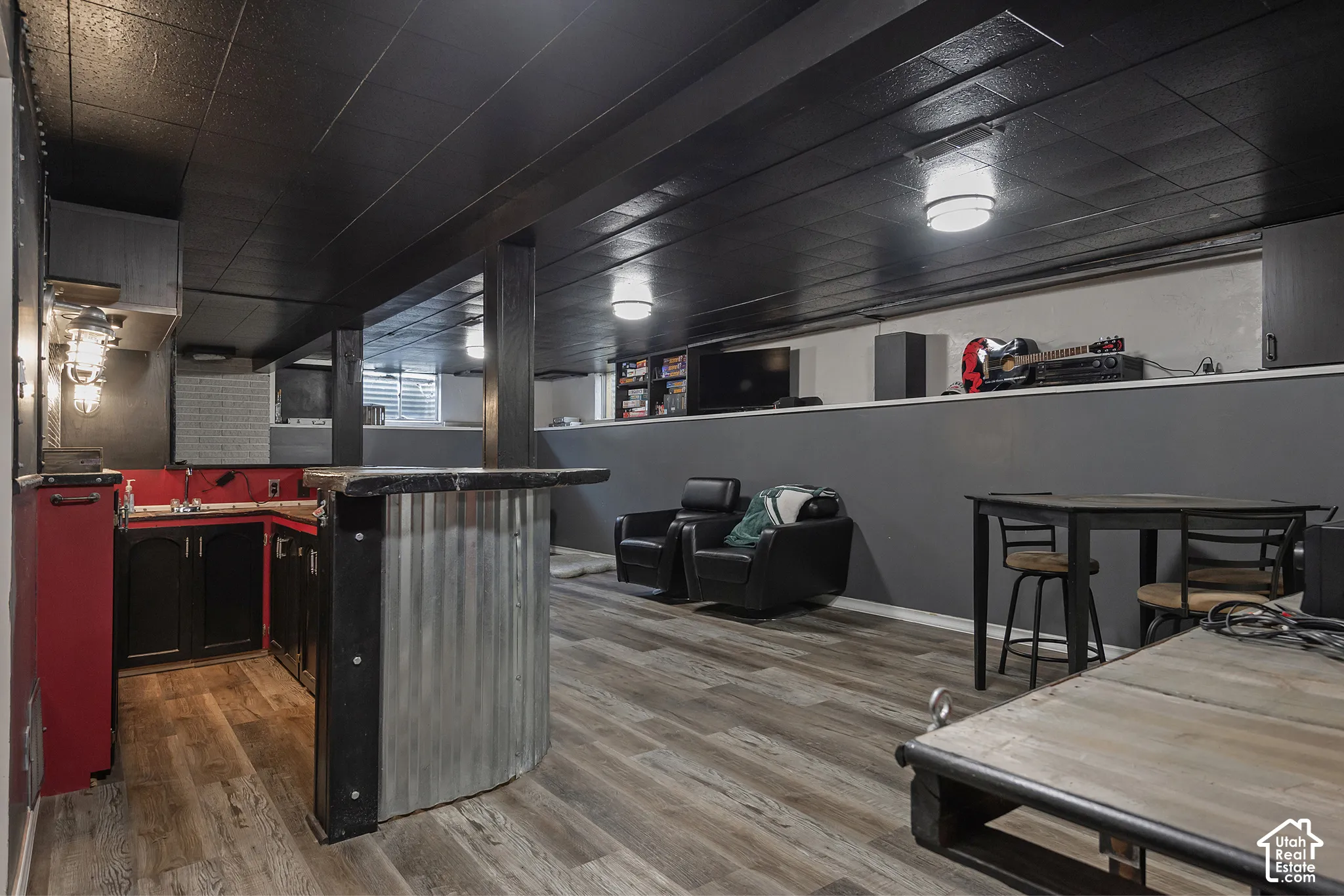 Custom wet bar featuring corrugated metal siding, dark cabinetry, wood-finish flooring, and exposed ceiling beams