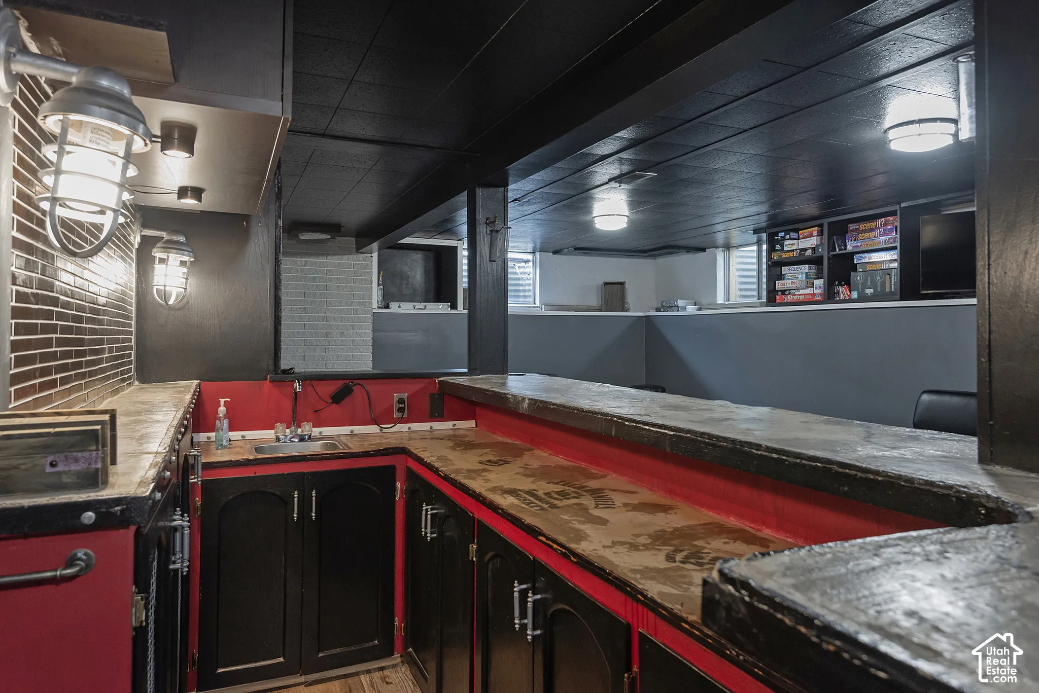 Built-in wet bar featuring custom cabinetry, a prep sink, stone-finish countertops, industrial-style wall-mounted lighting, and built-in shelving