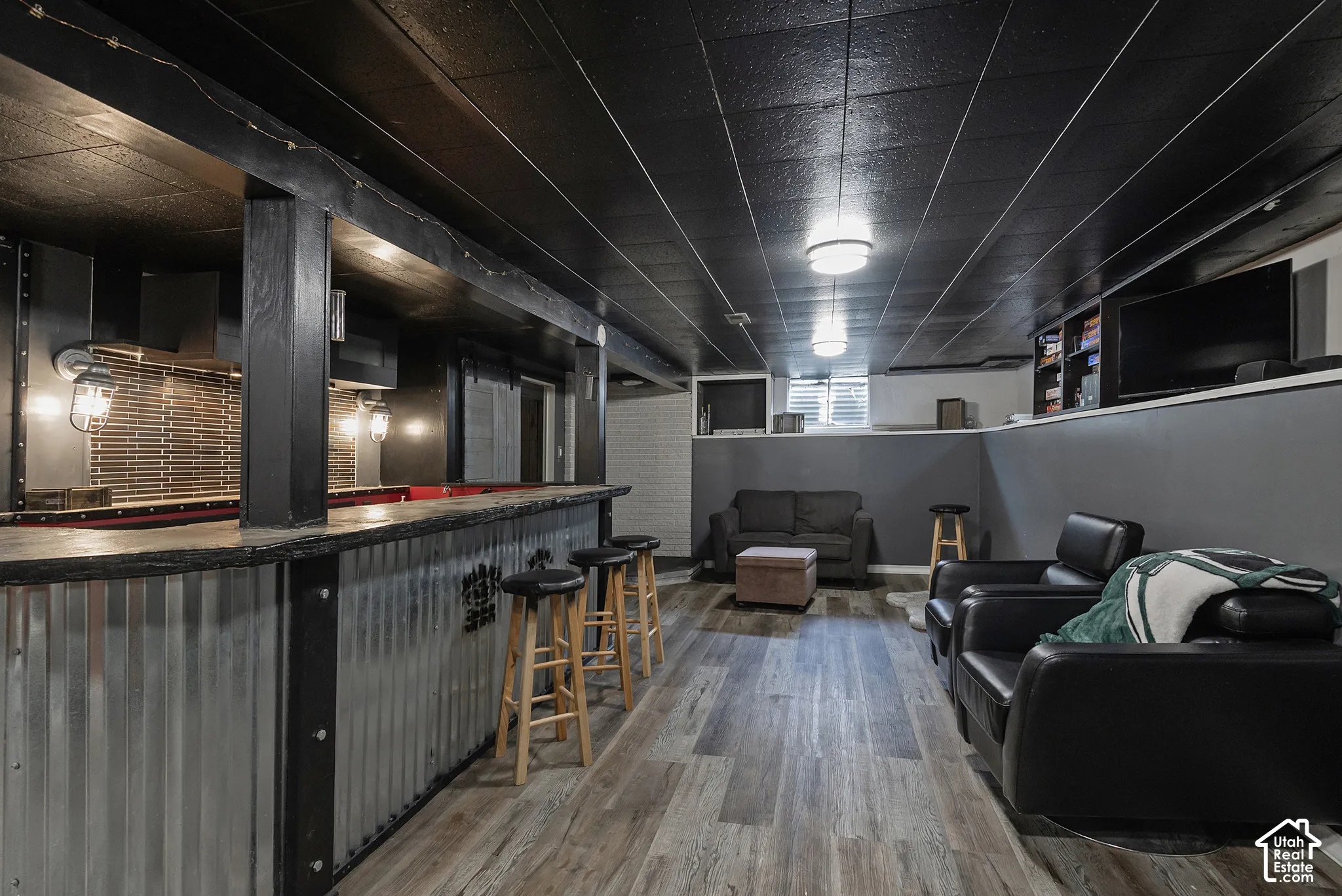 Wet bar featuring a corrugated metal front, tile backsplash, wood-finish flooring, and recessed ceiling lighting