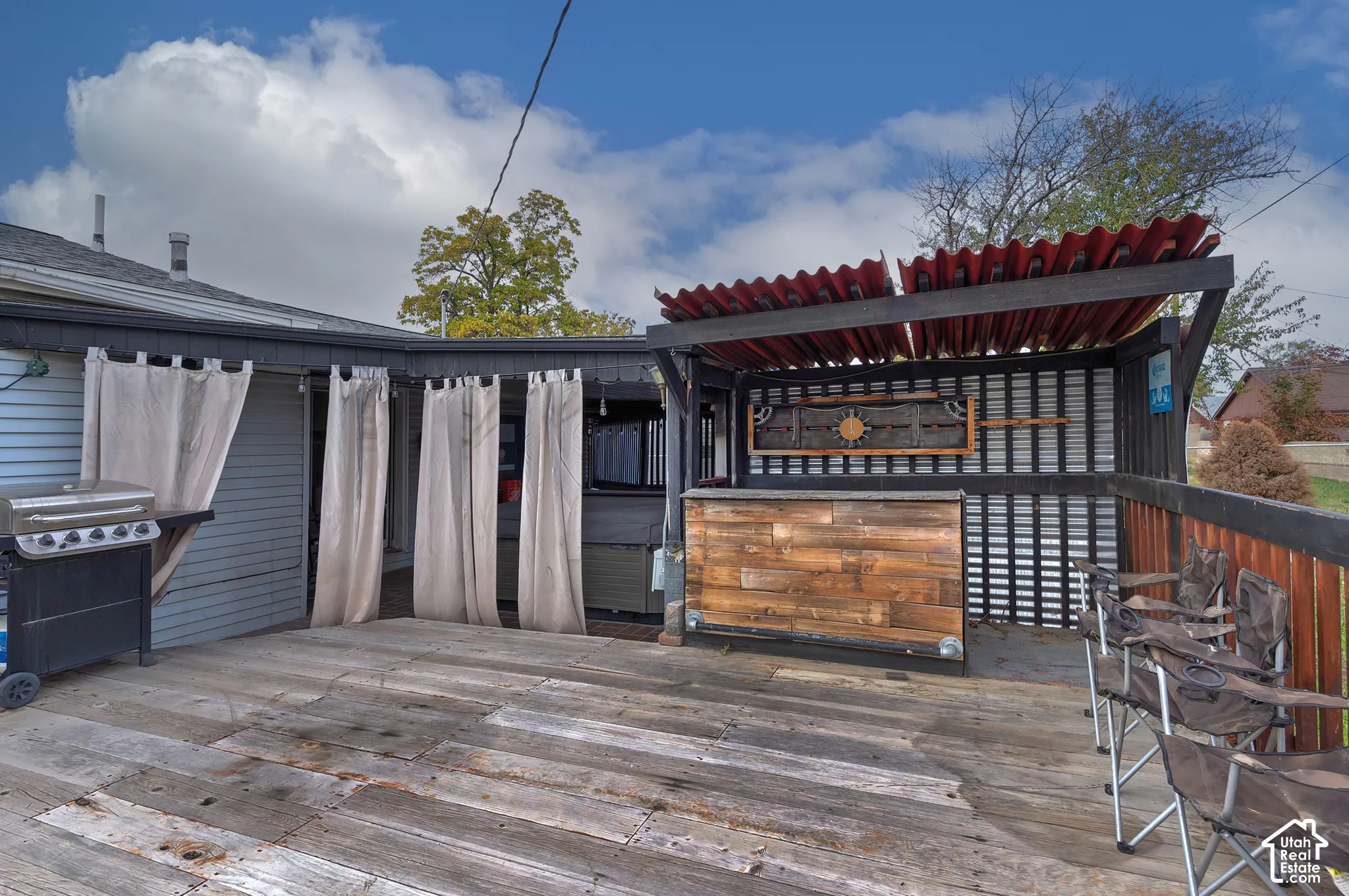 Outdoor wooden deck featuring a built-in bar, metal roof pergola, and slatted privacy screening