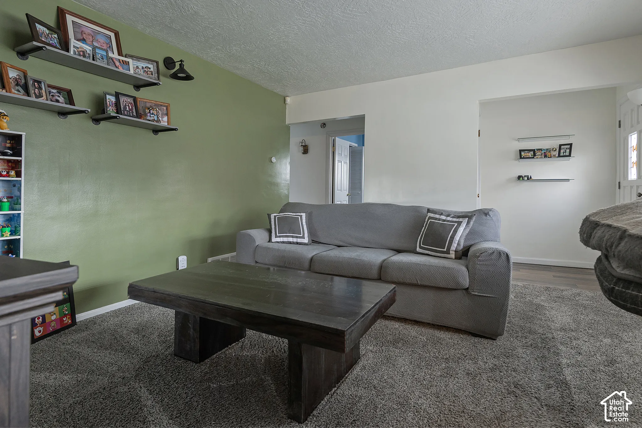 Living area featuring wall-mounted metal shelving, a textured accent wall, and wood-finish flooring