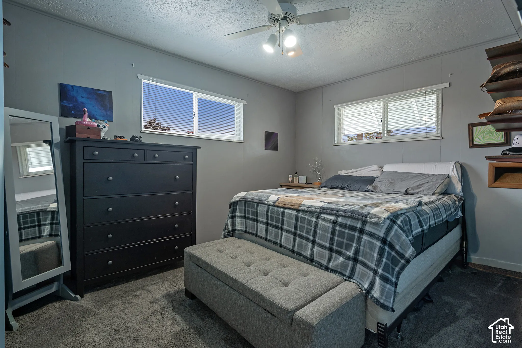 Neutral-toned interior space featuring dual-pane horizontal sliding windows, wall-to-wall carpeting, and a ceiling-mounted fan with integrated lighting