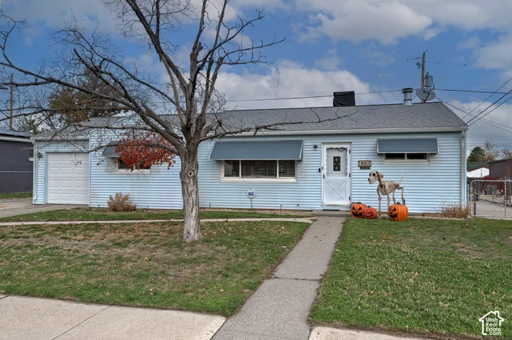 Single-story residence featuring light-blue horizontal siding, an attached one-car garage, metal window awnings, and a concrete walkway