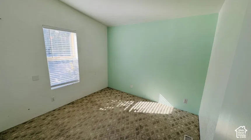 Interior room featuring patterned carpeting, one accent wall, and a window with horizontal blinds