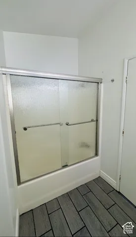 Shower enclosure featuring sliding textured-glass doors, a metal frame, and tile flooring