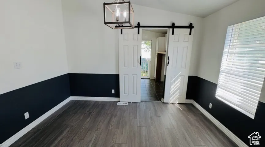 Wood-finish flooring, dual-tone wall treatment, sliding barn-style doors with matte black hardware, and an open-frame industrial pendant light fixture
