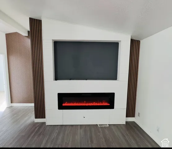 Custom-built media wall featuring shiplap detailing, integrated electric fireplace, wood-slat accent wall, and wood-finish flooring