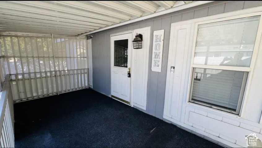 Covered porch featuring a metal-frame enclosure, exterior wall-mounted lantern lighting, and a single-entry door with glass detailing